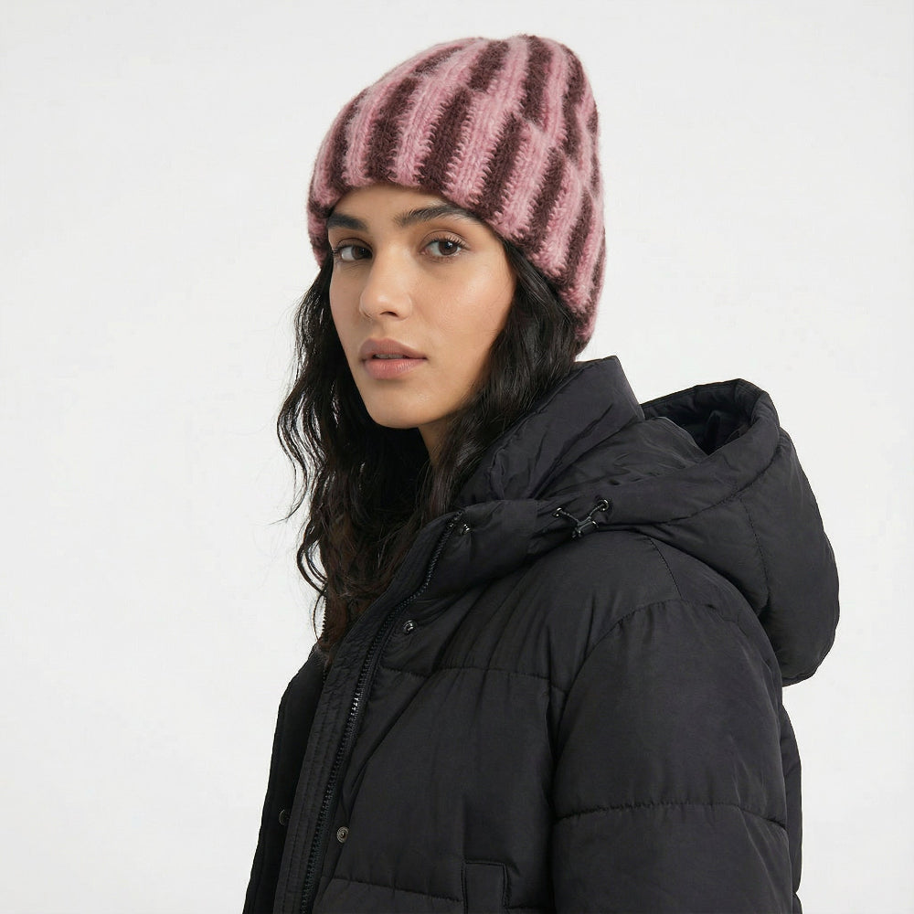 Woman wearing a coral pink and brown striped fluffy knit beanie, showcasing soft, textured insulation.
