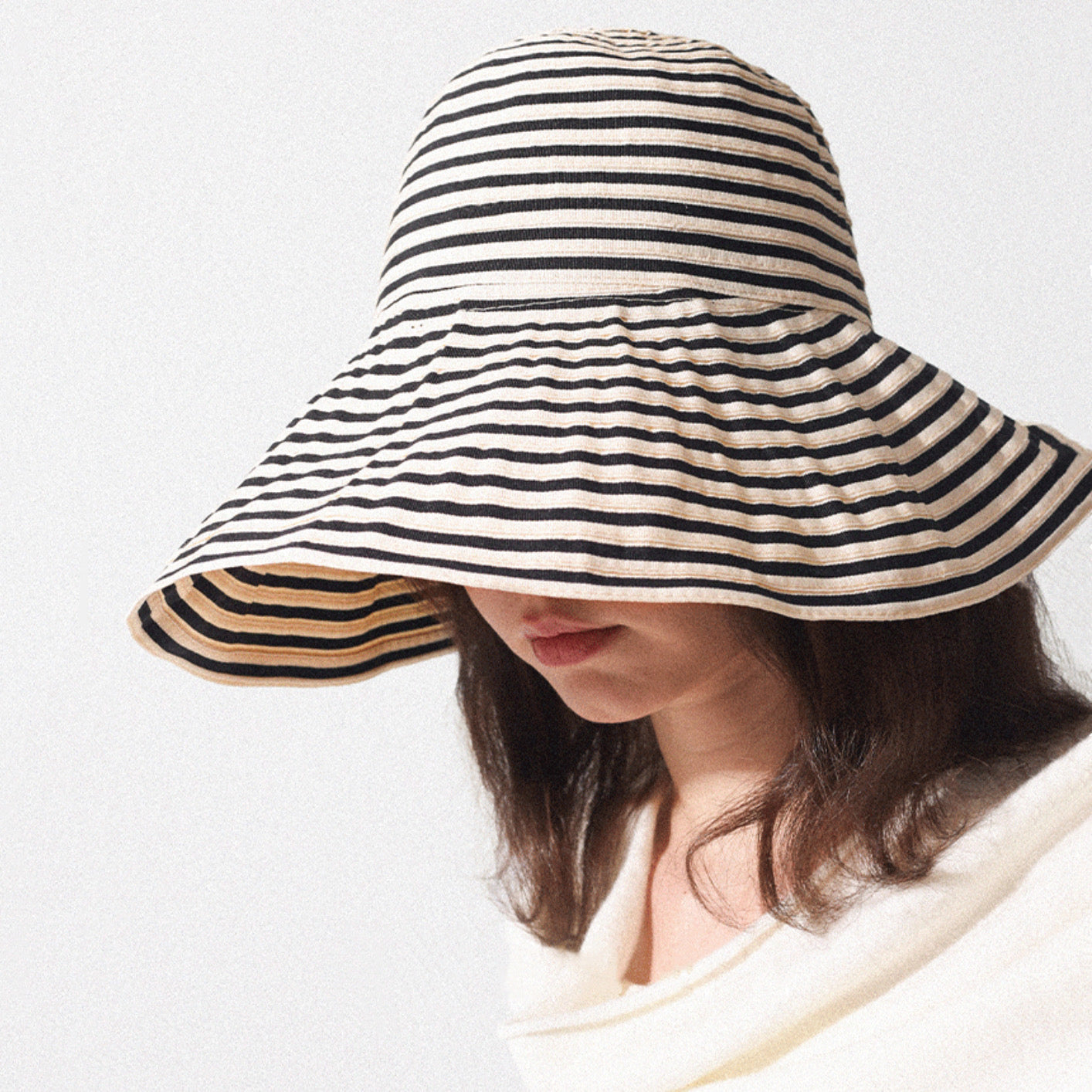 Model wearing Striped Wide Brim Bucket Hat in khaki black, highlighting the classic horizontal stripes.