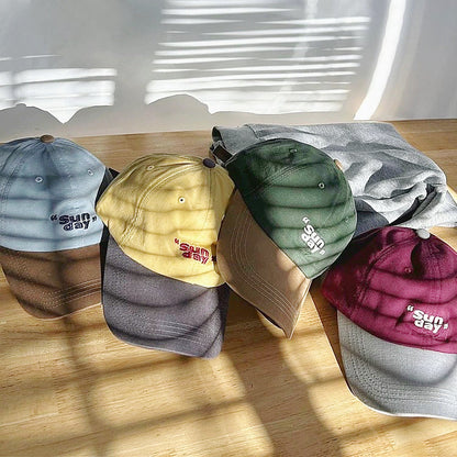 Four Sun Day caps in blue, yellow, green, and burgundy with contrasting brims in a breathable cotton blend.
