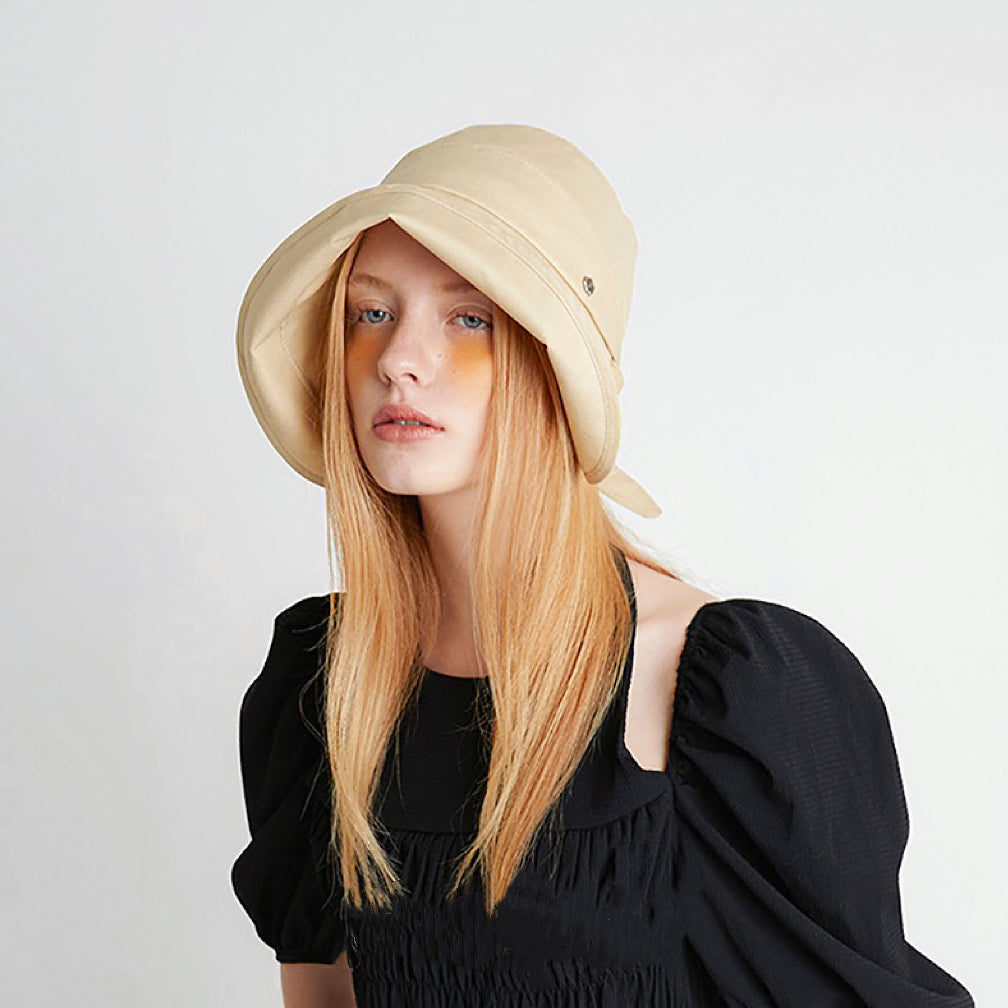 Fashion shot of the cream yellow sun shield hat paired with a black summer dress.