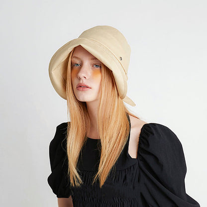 Fashion shot of the cream yellow sun shield hat paired with a black summer dress.