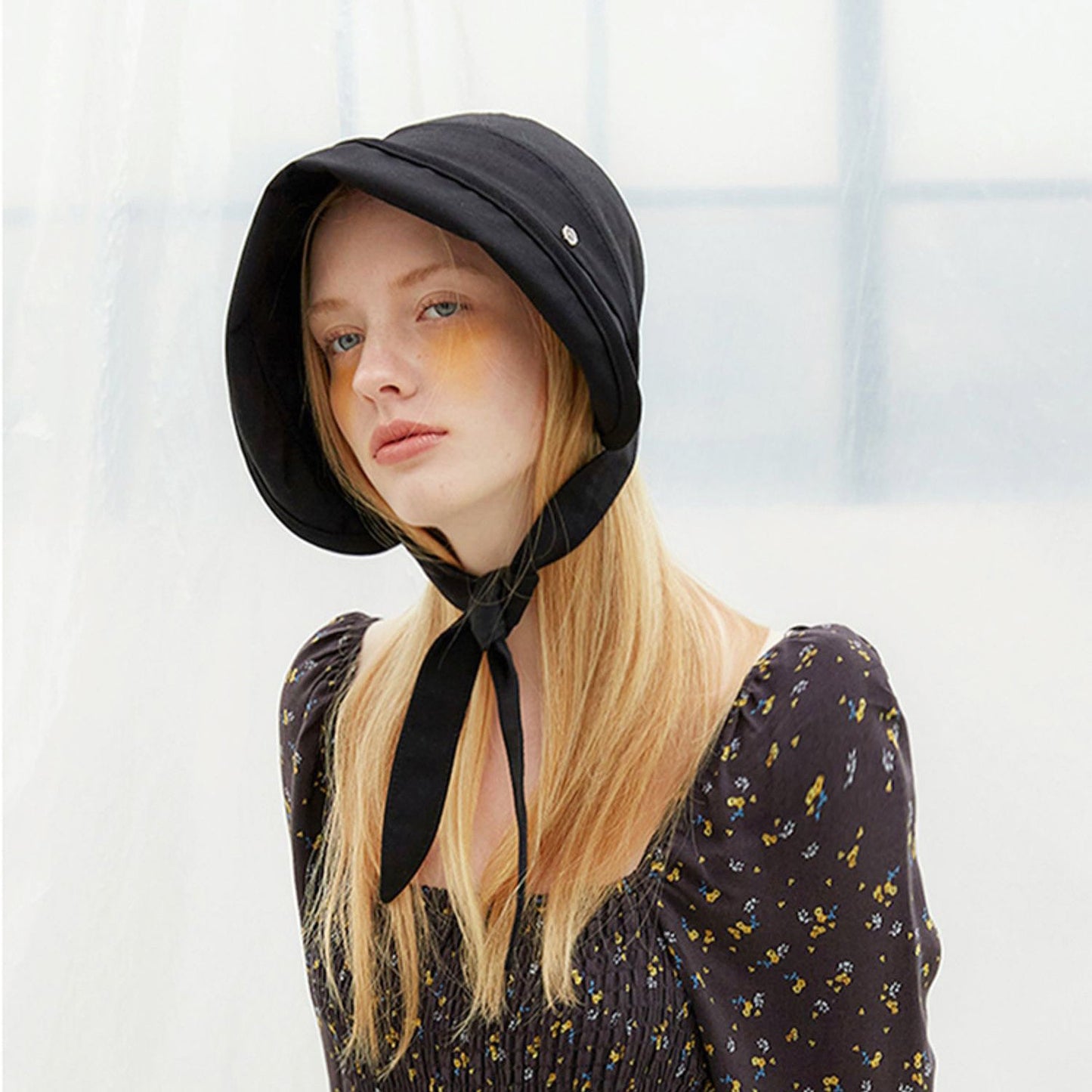 Front view of a model wearing the black ribbon bucket hat with streamers tied.