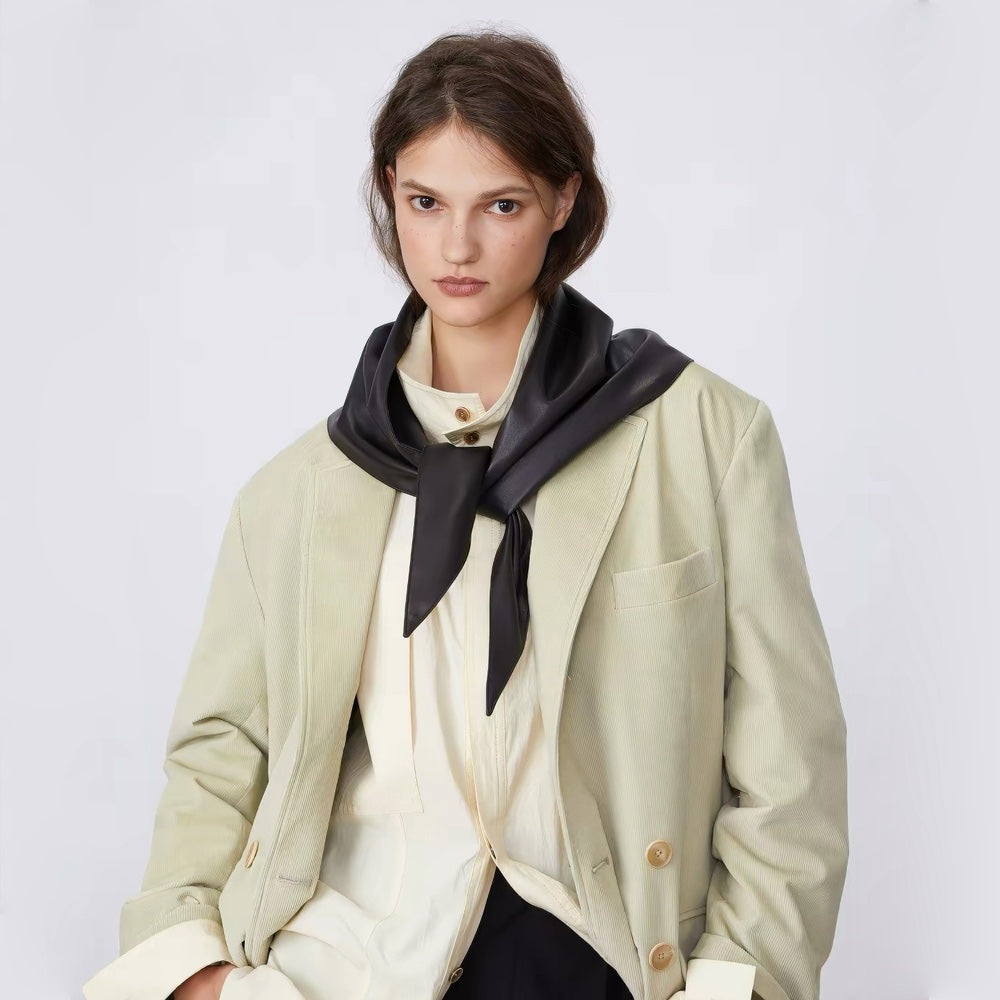 Model styled in a black leather triangle scarf paired with an off-white blazer for an office chic look.