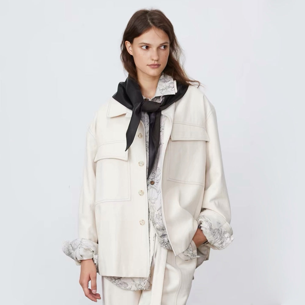 Model wearing a black reversible triangle scarf with the soft fleece side facing outward tied in a front knot over a jacket.
