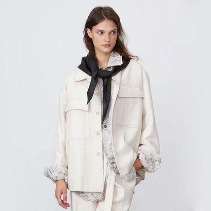 Model wearing a black reversible triangle scarf with the soft fleece side facing outward tied in a front knot over a jacket.