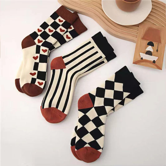 Front view of Three pairs of thick retro cotton-blend socks with unique patterns: hearts, stripes, and checker.