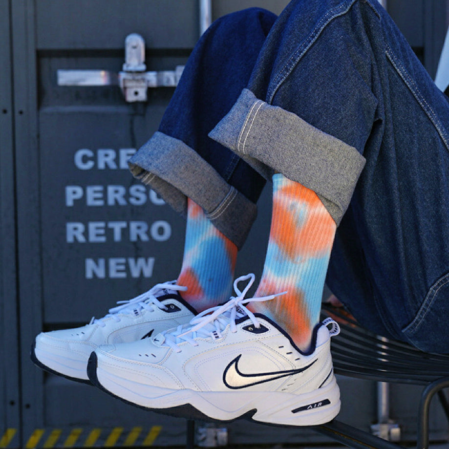 Model wearing a pair of Tie Dye cotton Socks in blue and orange, easy to pack for travel and errands.