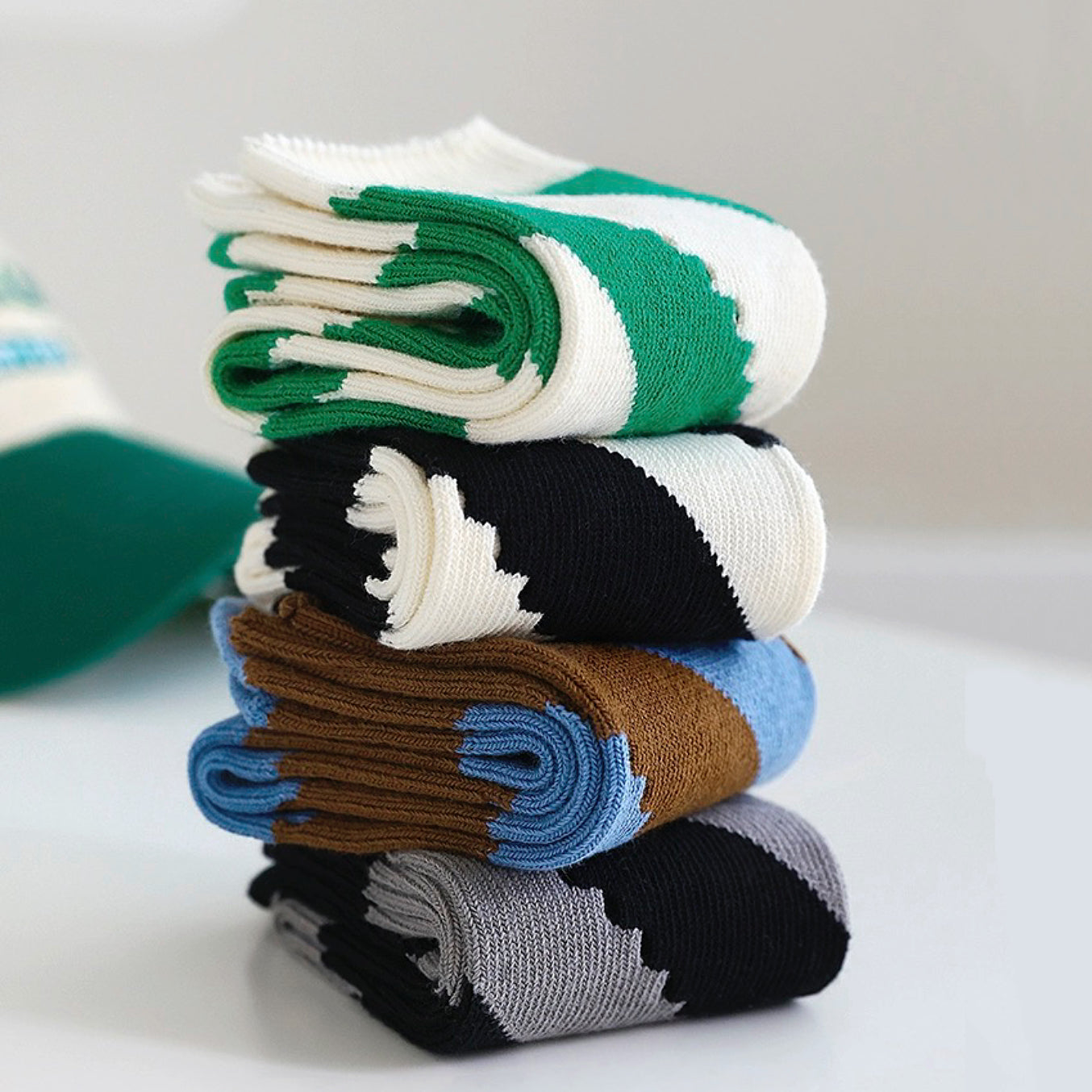 Angled view of Stacked twill cutout socks in green, black, brown, and gray with white and blue accents.