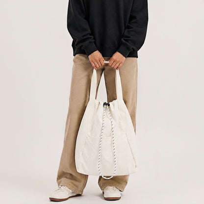 Model holding the off-white 2-way convertible tote bag by its shoulder handles.