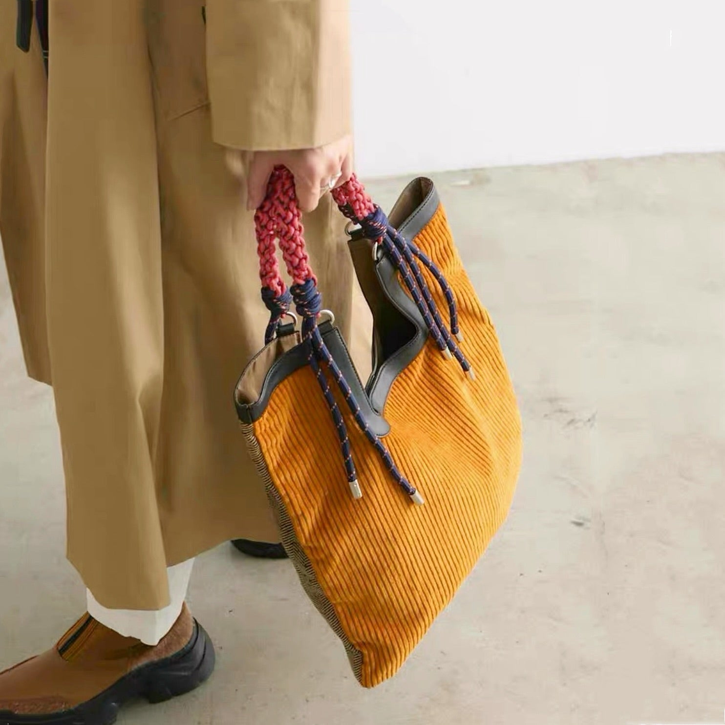 Lifestyle shot of  versatile tote bag showing the contrast between  mustard corduroy front and  braided rope handle details.