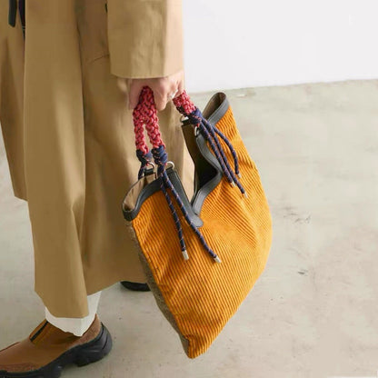 Lifestyle shot of  versatile tote bag showing the contrast between  mustard corduroy front and  braided rope handle details.