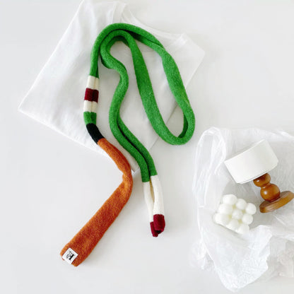 Angled view of colorblocked skinny polyester scarf in green, orange, white, and burgundy, easy for travel.