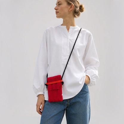 Model styling the bold red pleated knit mini crossbody pouch over daily casual wear.