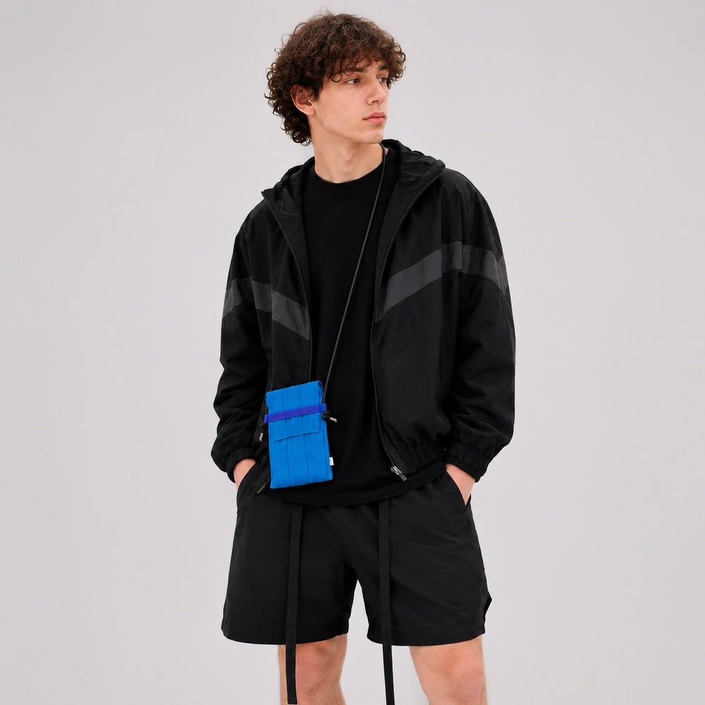 Male model wearing the sky blue micro knit pleat bag over a black technical jacket.