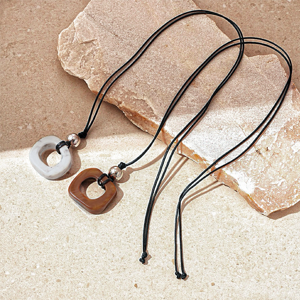 Front view of two pieces of Wild Grace Geometric Pendant Necklace in brown and grey.