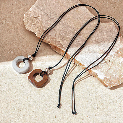 Front view of two pieces of Wild Grace Geometric Pendant Necklace in brown and grey.