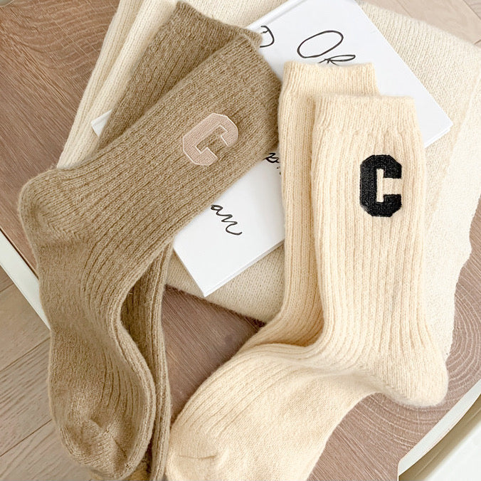 Angled view of two paris of ribbed wool C socks in khaki and beige.