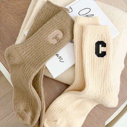 Angled view of two paris of ribbed wool C socks in khaki and beige.